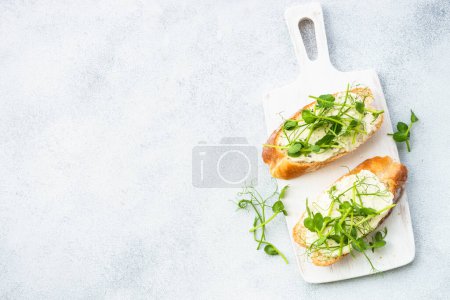 Téléchargez les photos : Toast au fromage à la crème et aux micro-légumes. Alimentation saine, plat végétarien. Pose plate sur blanc. - en image libre de droit