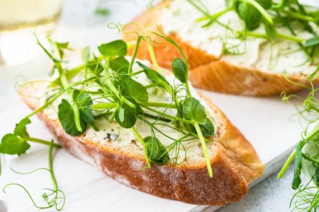 Photo for Toast with micro greens, green pea and cream cheese at blue. Healthy food snack, vegetarian. Close up. - Royalty Free Image