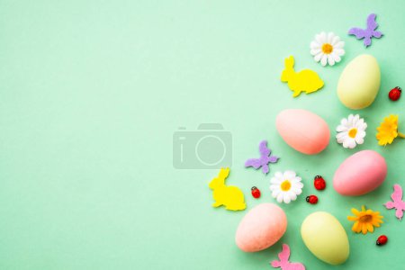 Photo for Easter background. Eggs, rabbit, spring flowers and butterfly. Flat lay mock up at green background. - Royalty Free Image