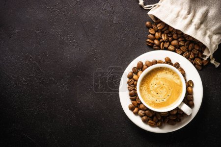Cup of coffee and sack of coffee beans at dark table . Top view image with copy space.