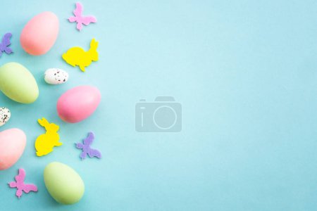 Photo for Easter background on blue. Eggs, rabbit, spring flowers and butterfly. Flat lay with copy space. - Royalty Free Image