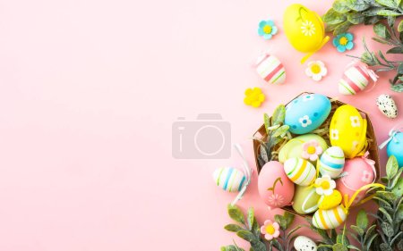 Easter eggs in the nest on pink background. Easter decor. Flat lay image with copy space.