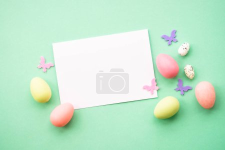 Foto de Feliz Pascua. Huevos, conejo, flores de primavera y mariposa. Imagen plana en el fondo verde. - Imagen libre de derechos