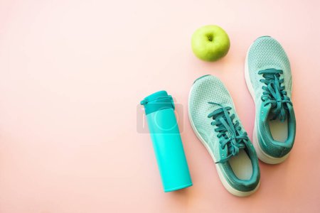 Foto de Entrenamiento y concepto de estilo de vida saludable. Zapatillas, manzana verde y botella de agua. Piso con espacio de copia. - Imagen libre de derechos