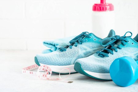 Foto de Fondo de fitness, equipo deportivo en blanco. Zapatillas, mancuernas, toallas y cinta métrica. - Imagen libre de derechos