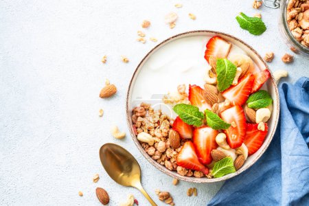 Photo for Yogurt with granola, nuts and strawberries on white. Healthy snack or breakfast, fruit salad. Top view with copy space. - Royalty Free Image