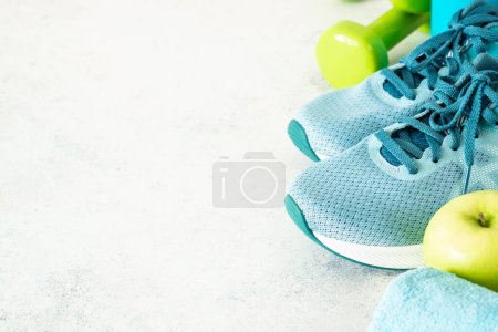 Photo for Fitness equipment on white. Sneakers, dumbbells and green apple. Training, workout and fitness concept. - Royalty Free Image