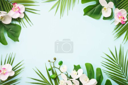Photo for Summer tropical background. Tropical leaves and flowers on blue. Flat lay image with copy space. - Royalty Free Image