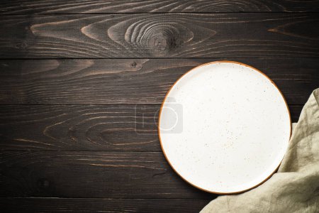 Photo for White craft plate at dark wooden table. Top view image with copy space. - Royalty Free Image