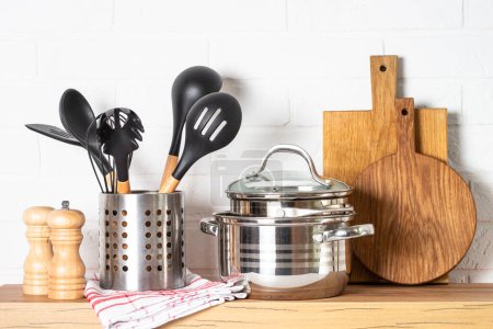 Kitchen utensils. Cooking tools with cooking pots, wooden cutting boards at white modern kitchen interior.
