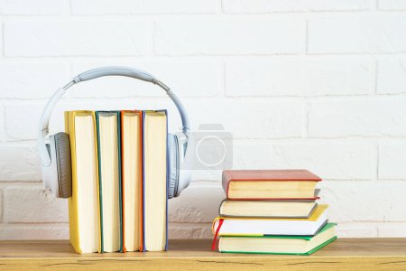Concept de livres audio. Casques sans fil et livres de couleurs à la table en bois fond blanc.