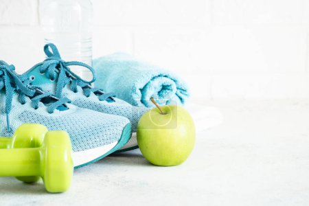 Photo for Fitness equipment on white. Sneakers, dumbbells and green apple. Training, workout and fitness concept. - Royalty Free Image