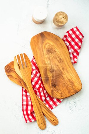 Foto de Tabla de aceitunas, aceite de oliva, cuchara y mantel sobre mesa de cocina blanca. Fondo alimenticio con espacio de copia. - Imagen libre de derechos