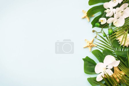 Photo for Tropical background, summer holidays. Tropical leaves and flowers on blue. Flat lay image with copy space. - Royalty Free Image