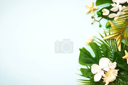 Téléchargez les photos : Feuilles de palmier, fleurs et coquillages sur bleu. Vue supérieure avec espace de copie. - en image libre de droit