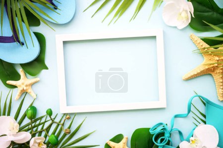 Photo for Summer holidays background. Palm leaves, hat, flip flop, shells and photo frame on blue background. Flat lay with copy space. - Royalty Free Image