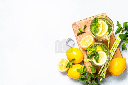 Téléchargez les photos : Citronnade en verre avec des citrons frais et de la menthe. Boisson froide d'été vue de dessus avec espace de copie. - en image libre de droit