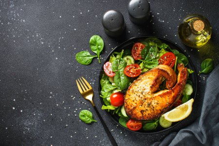 Foto de Filete de salmón y ensalada verde fresca sobre fondo negro. Dieta Keto, comida saludable. Espacio de copia vista superior. - Imagen libre de derechos