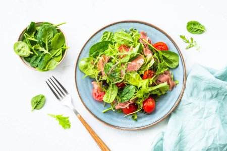 Téléchargez les photos : Salade verte aux feuilles fraîches, tomates et confiture à table blanche. Vue supérieure avec espace de copie. - en image libre de droit