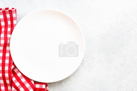 Téléchargez les photos : Table de cuisine avec plaque blanche et nappe rouge. Fond alimentaire avec espace de copie. - en image libre de droit