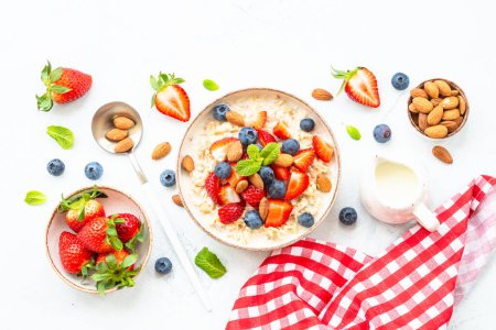 Foto de Avena porrige con bayas frescas y frutos secos sobre fondo blanco. Desayuno saludable, vista superior con espacio para copiar. - Imagen libre de derechos