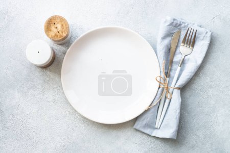 Photo for White plate, shaker and cutlery on stone table. Table setting, flat lay image. - Royalty Free Image