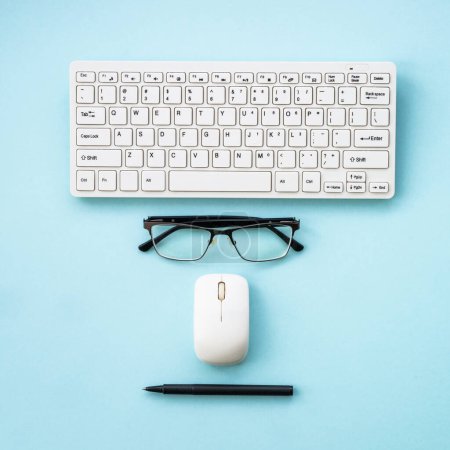 Photo for Office workspace with keyboard, notepad, glasses, pen and coffee cup. Flat lay image on blue, minimal. - Royalty Free Image