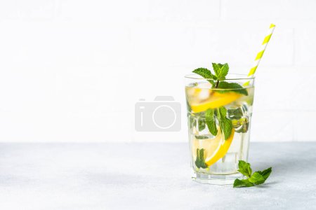 Téléchargez les photos : Citronnade en verre sur table blanche. Boisson froide d'été avec glace. - en image libre de droit
