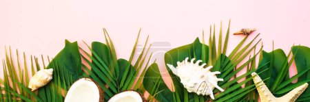 Photo for Summer flat lay background. Tropical leaves, palm leaves, coconut and sea shells on pink background. Long banner format. - Royalty Free Image