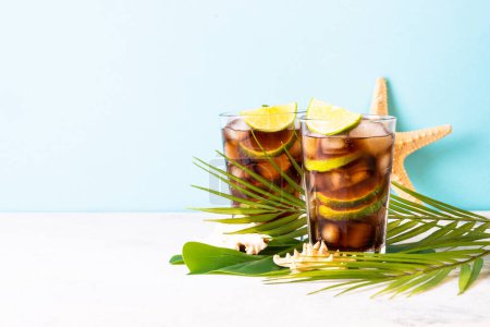 Photo for Summer drink. Cuba Libre or iced tea with palm leaves and sea shells. Refreshing. - Royalty Free Image