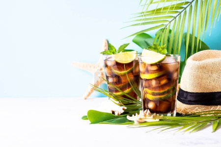 Photo for Cuba Libre iced drink, alcoholic with palm leaves and sea shells. Tropical vacation. - Royalty Free Image