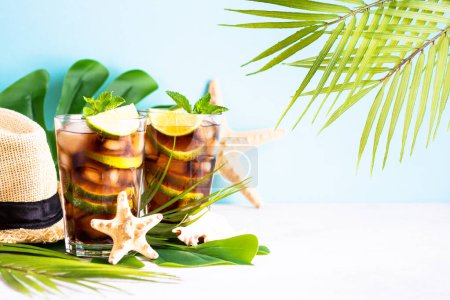 Photo for Cuba Libre alcoholic cocktail, iced drink with palm leaves and sea shells. Tropical vacation. - Royalty Free Image