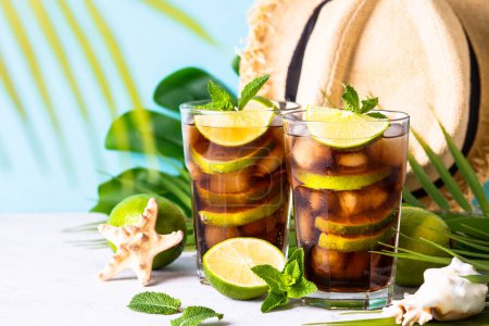 Téléchargez les photos : Un verre d'été. Cuba Libre ou thé glacé aux feuilles de palmier et coquillages. Vacances tropicales. - en image libre de droit