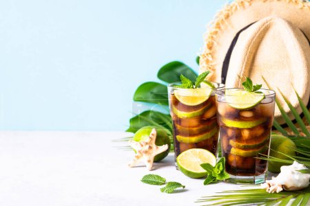 Photo for Cuba Libre alcoholic cocktail, iced drink with tropical leaves and sea shells. Summer vacation holidays. - Royalty Free Image