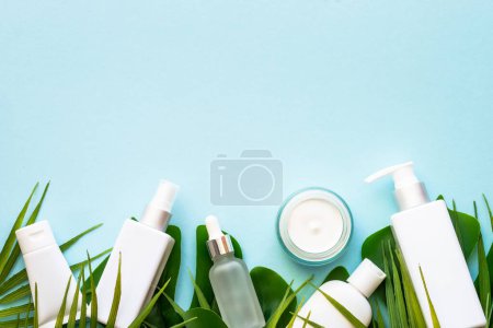 Téléchargez les photos : Cosmétique d'été, ensemble de produits cosmétiques avec des feuilles de palmier sur bleu. Vue du dessus. - en image libre de droit