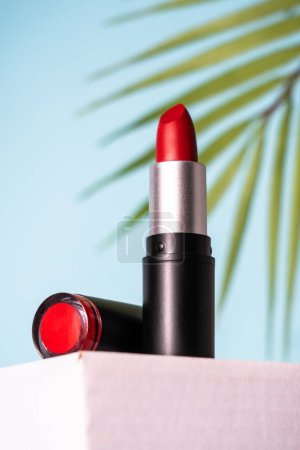 Foto de Lápiz labial en el podio con fondo azul. Maquillaje, producto cosmético. - Imagen libre de derechos