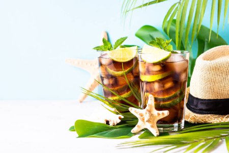 Photo for Summer drink. Cuba Libre or iced tea with palm leaves and sea shells. Tropical vacation. - Royalty Free Image