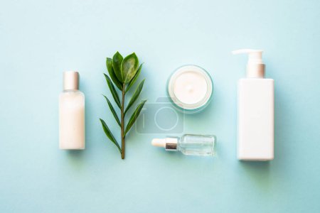 Photo for Natural cosmetic products. Cream, serum, tonic with green leaves. Top view on blue background. - Royalty Free Image