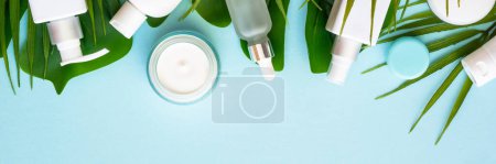 Photo for Natural cosmetic products. Cream, serum, tonic with green tropical leaves. Long banner format. - Royalty Free Image
