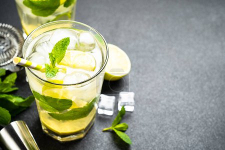 Téléchargez les photos : Mojito au rhum et citron vert sur fond noir. Boisson glacée estivale traditionnelle. - en image libre de droit