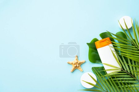 Foto de Productos de protector solar sobre fondo azul con hojas de palma. Protección solar. Imagen plana con espacio para texto. - Imagen libre de derechos