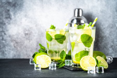 Photo for Mojito with rum, mint and lime on black background. Tradition Summer drink with shaker and bar utensils. - Royalty Free Image