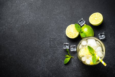 Photo for Mojito with rum, lime, mint and ice on black background. Tradition Summer drink. Flat lay with copy space. - Royalty Free Image