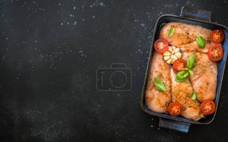 Foto de Filete de pollo, pechuga de carne de pollo cruda con especias y verduras en la sartén. Vista superior con espacio para la receta, listo para cocinar en el horno. - Imagen libre de derechos