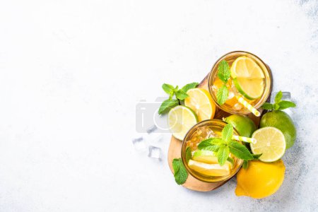 Photo for Summer tea with lemon, lime, mint and ice. Cold lemonade, iced tea, summer drink, white background. Top view with copy space. - Royalty Free Image