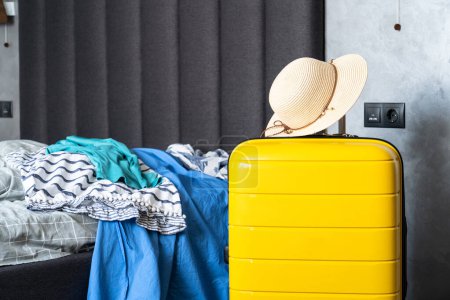Foto de Maleta con paño de verano y sombrero en el dormitorio. Concepto de viaje, equipaje de embalaje. - Imagen libre de derechos
