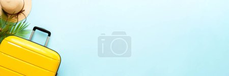 Photo for Summer holidays, traveling concept. Suitcase, hat and flip flops on blue background. Long banner format. - Royalty Free Image