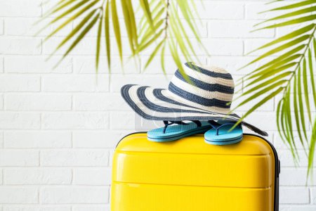 Photo for Summer holidays, traveling concept. Suitcase, hat and flip flops with palm leaves. - Royalty Free Image