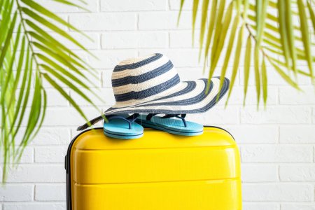Foto de Vacaciones de verano, concepto de viaje. Maleta, sombrero y chanclas con hojas de palma. - Imagen libre de derechos