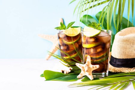 Photo for Cuba Libre iced drink, alcoholic with palm leaves and sea shells. Tropical vacation. - Royalty Free Image